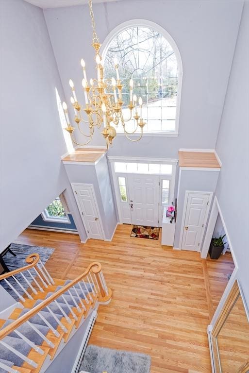 foyer entrance featuring a high ceiling, wood-type flooring, and a notable chandelier