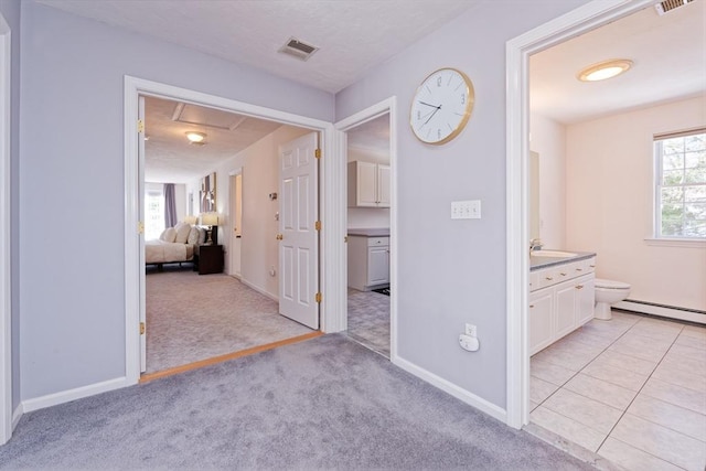 hall featuring sink, a baseboard heating unit, and light colored carpet