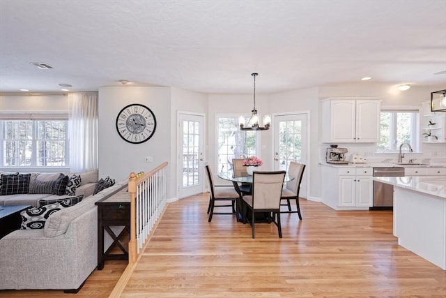 dining area featuring an inviting chandelier, sink, and light wood-type flooring