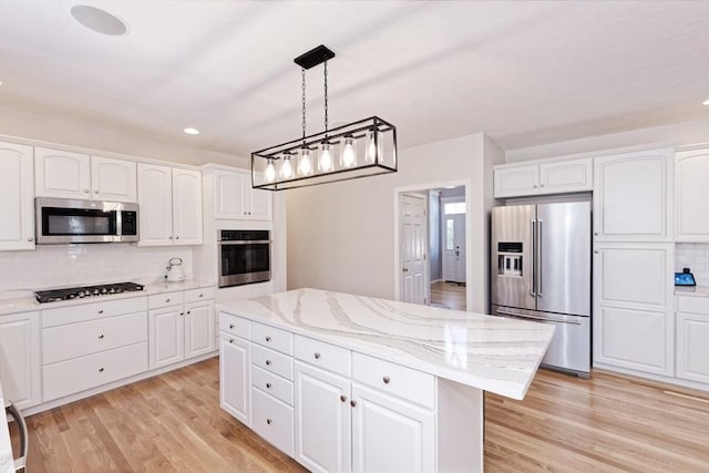 kitchen featuring a kitchen island, white cabinets, hanging light fixtures, stainless steel appliances, and light wood-type flooring