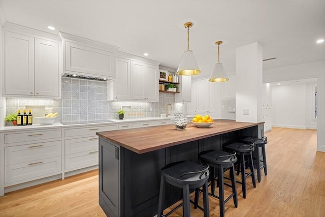 130 Mount Auburn St Unit 310, Cambridge, MA 02138 - kitchen with butcher block countertops, backsplash, white cabinetry, open shelves, and light wood-type flooring