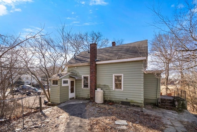 back of house with a chimney and fence