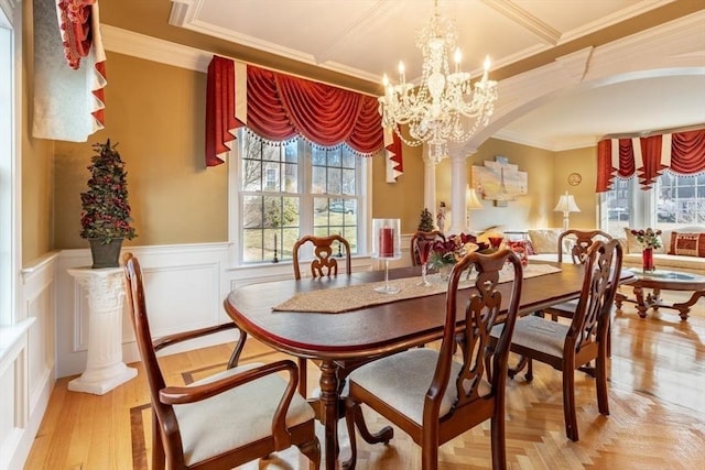 dining area featuring a chandelier, ornamental molding, and decorative columns