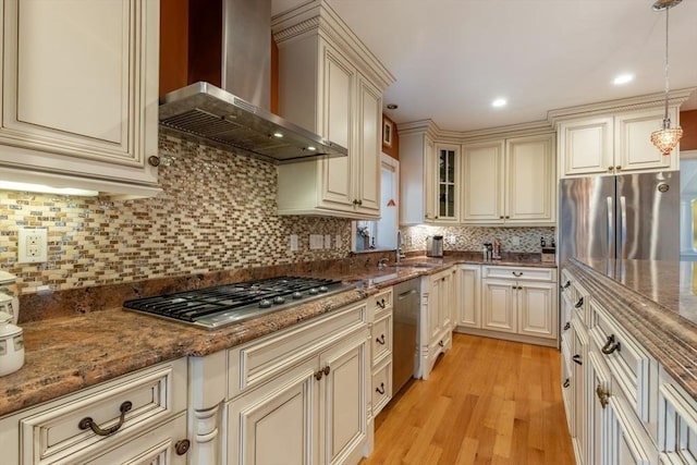 kitchen featuring backsplash, wall chimney range hood, and hanging light fixtures