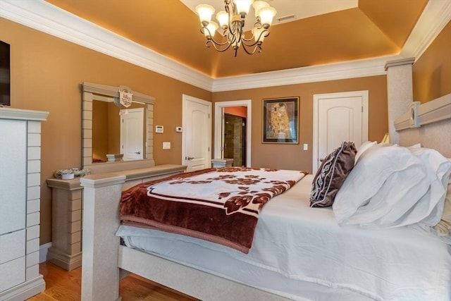 bedroom with hardwood / wood-style floors, a notable chandelier, a raised ceiling, and crown molding