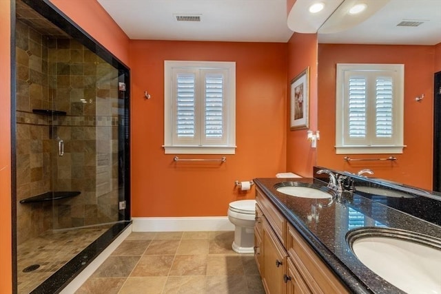 bathroom featuring a shower with door, vanity, a healthy amount of sunlight, and toilet