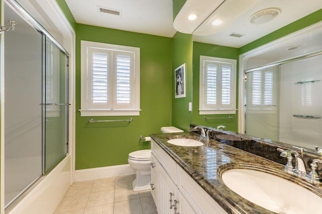 full bathroom with tile patterned floors, vanity, toilet, and bath / shower combo with glass door