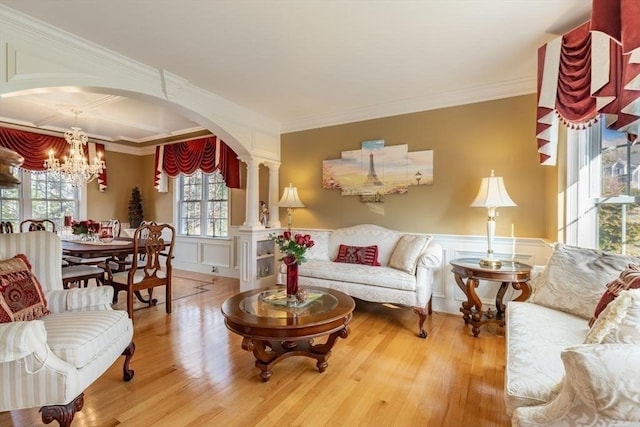 living room with hardwood / wood-style flooring, ornate columns, ornamental molding, and a chandelier