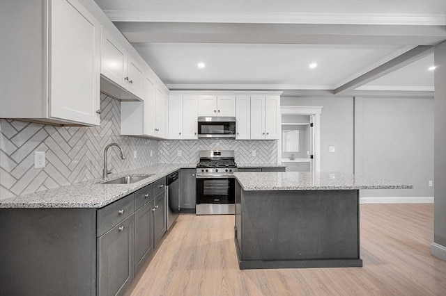 kitchen featuring sink, appliances with stainless steel finishes, light stone counters, white cabinets, and a kitchen island