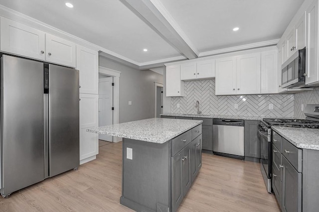 kitchen with stainless steel appliances, a kitchen island, gray cabinets, and white cabinets