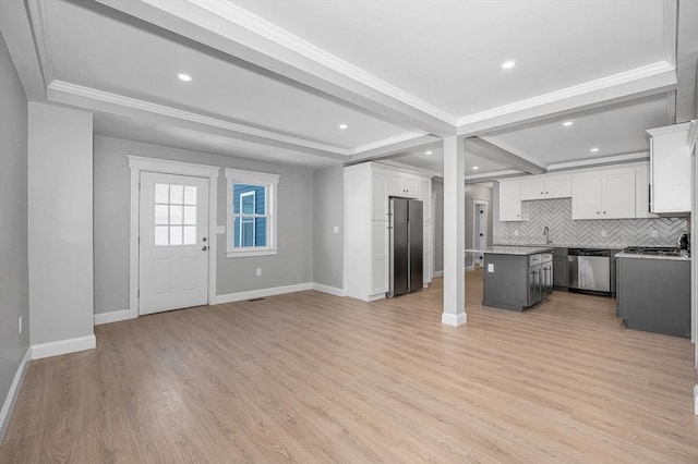 kitchen with white cabinetry, backsplash, stainless steel appliances, light hardwood / wood-style floors, and a kitchen island