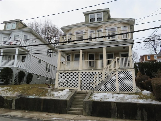 view of front of property with stairway, covered porch, and a balcony