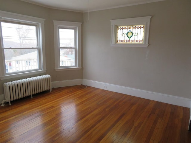 unfurnished room with ornamental molding, radiator, wood-type flooring, and baseboards