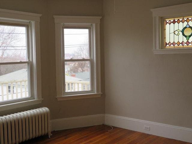 spare room with dark wood-style floors, baseboards, and radiator heating unit