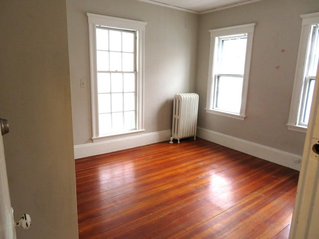 empty room with baseboards, hardwood / wood-style flooring, and radiator