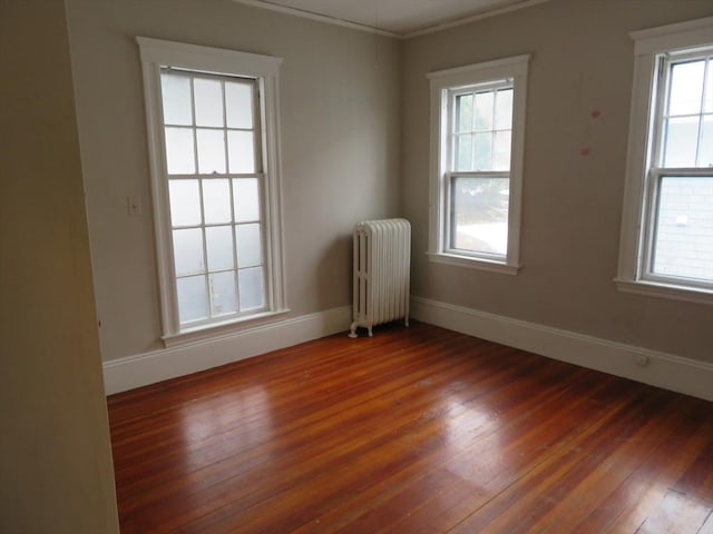 empty room with radiator, crown molding, baseboards, and hardwood / wood-style floors