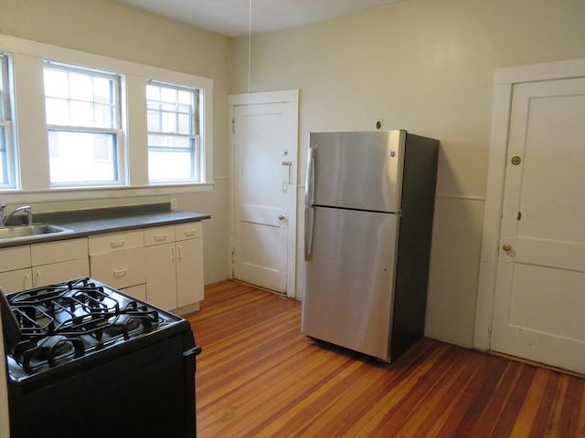 kitchen with light wood-style floors, black range with gas cooktop, a sink, and freestanding refrigerator