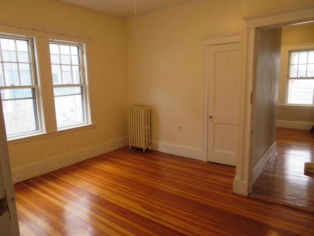 unfurnished room featuring radiator, baseboards, and wood finished floors