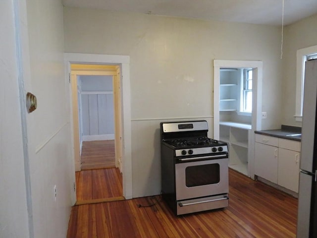 kitchen featuring appliances with stainless steel finishes, dark countertops, wood finished floors, and white cabinetry