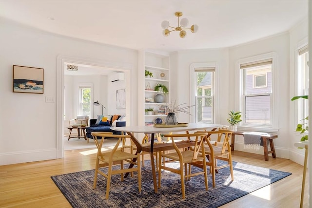 31 Kidder Ave Unit 31, Somerville, MA 02144 - dining space with light wood finished floors, a chandelier, an AC wall unit, built in shelves, and baseboards