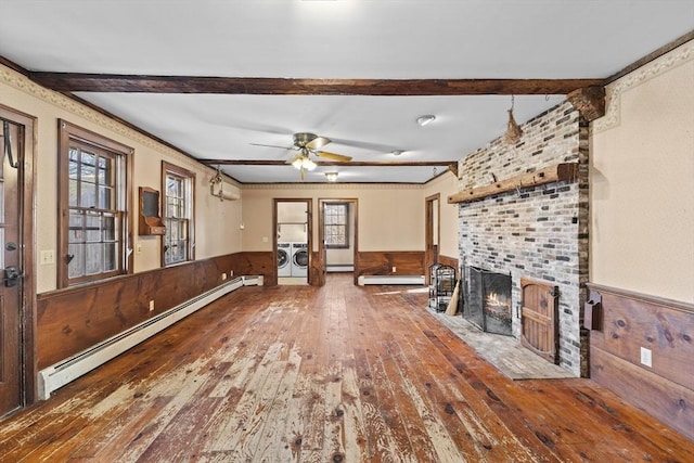 unfurnished living room with separate washer and dryer, baseboard heating, a fireplace, and wood-type flooring