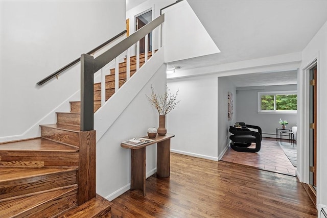 stairway featuring baseboards, baseboard heating, and wood finished floors