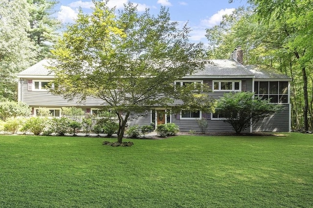 view of front facade with a chimney and a front lawn