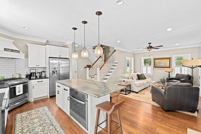 260 Beaver Dam Rd, Scituate, MA 02066 - kitchen with stainless steel appliances, a kitchen breakfast bar, open floor plan, premium range hood, and white cabinetry