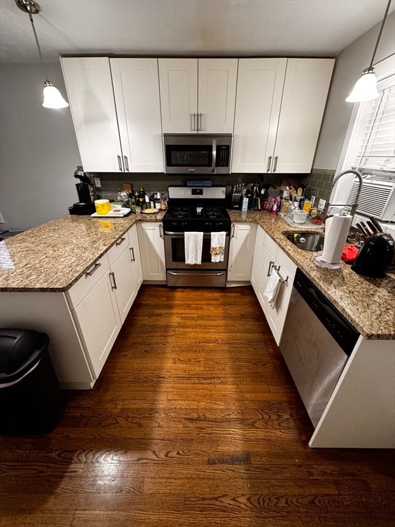 kitchen featuring kitchen peninsula, white cabinetry, pendant lighting, and stainless steel appliances