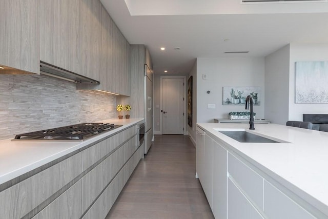 kitchen featuring tasteful backsplash, modern cabinets, light countertops, stainless steel gas cooktop, and a sink