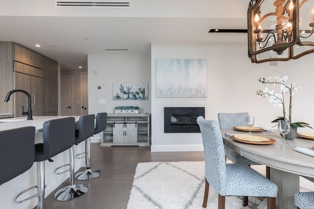 dining space with baseboards, visible vents, a glass covered fireplace, dark wood-style floors, and recessed lighting