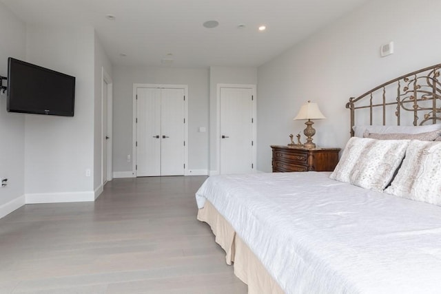 bedroom with a closet, recessed lighting, wood finished floors, and baseboards