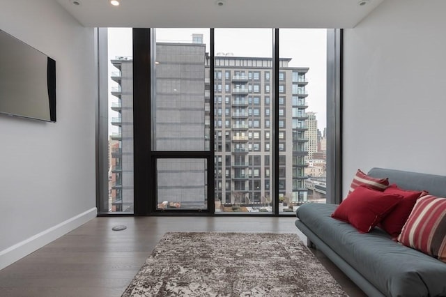 living area featuring recessed lighting, a city view, wood finished floors, baseboards, and floor to ceiling windows