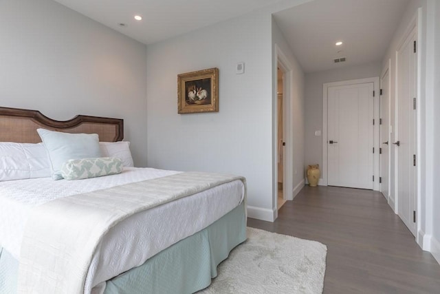 bedroom with baseboards, wood finished floors, visible vents, and recessed lighting