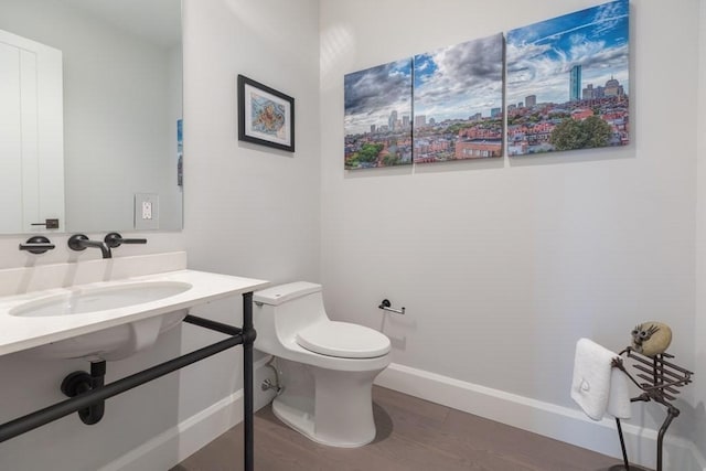 bathroom with baseboards, vanity, toilet, and wood finished floors