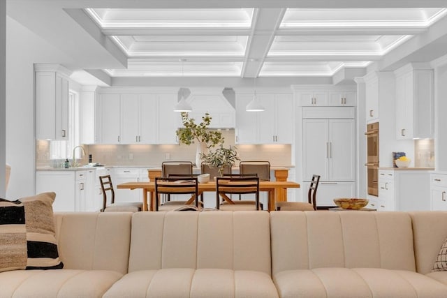 living area with coffered ceiling, crown molding, and beamed ceiling