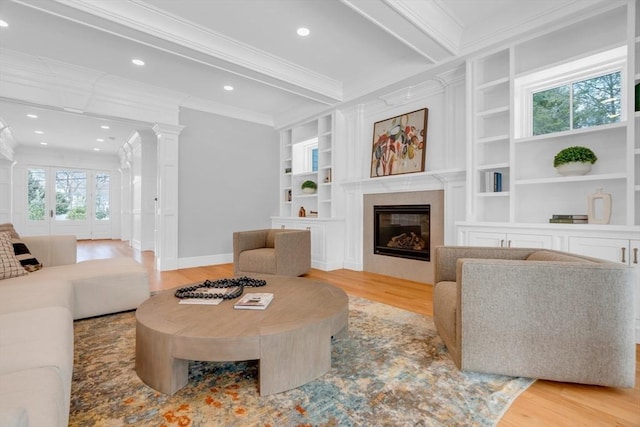 living room with light wood-type flooring, ornate columns, built in shelves, and ornamental molding