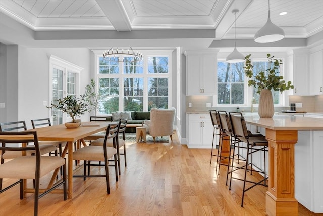 dining space with ornamental molding, light wood-type flooring, and beamed ceiling