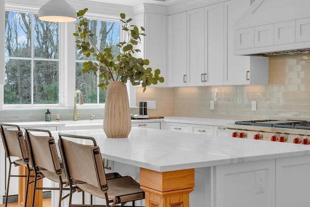 kitchen with white cabinetry, a kitchen bar, and light stone countertops