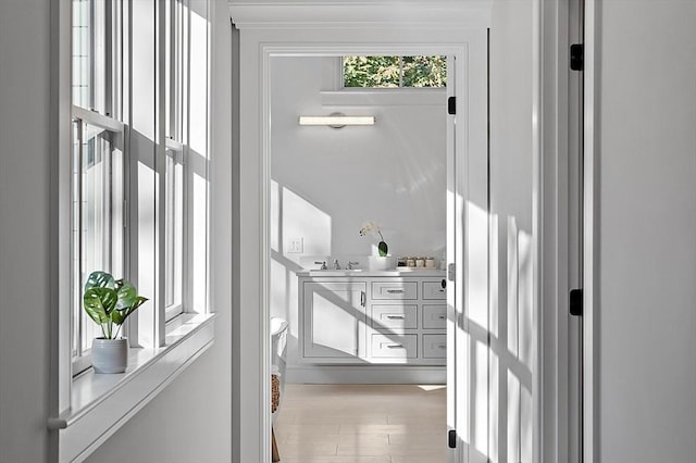 corridor with light wood-type flooring and a sink