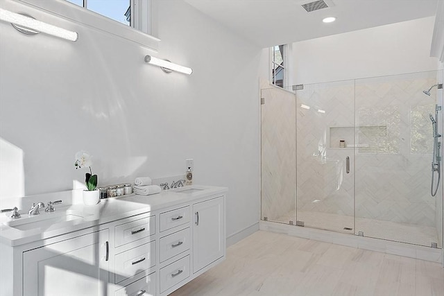 full bath featuring double vanity, a stall shower, visible vents, and a sink