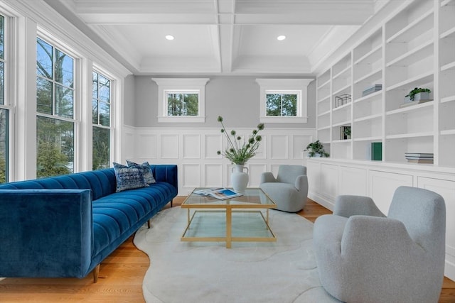 living area with light wood finished floors, coffered ceiling, beam ceiling, and a decorative wall