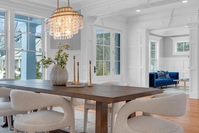 dining area featuring crown molding, plenty of natural light, a notable chandelier, and a decorative wall