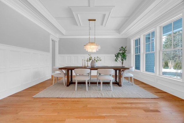 dining room with light wood finished floors, ornamental molding, and a decorative wall