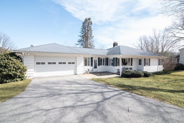 ranch-style house with a garage, driveway, a chimney, and a front yard