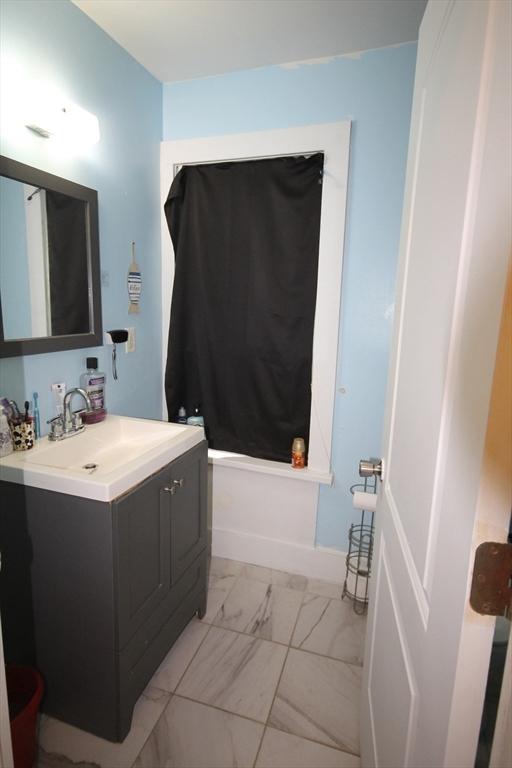 full bath with vanity, marble finish floor, and shower / bathtub combination with curtain