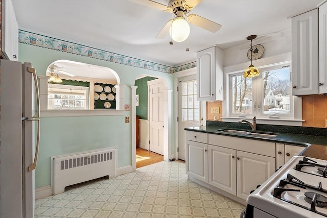 kitchen with white appliances, dark countertops, a sink, and radiator