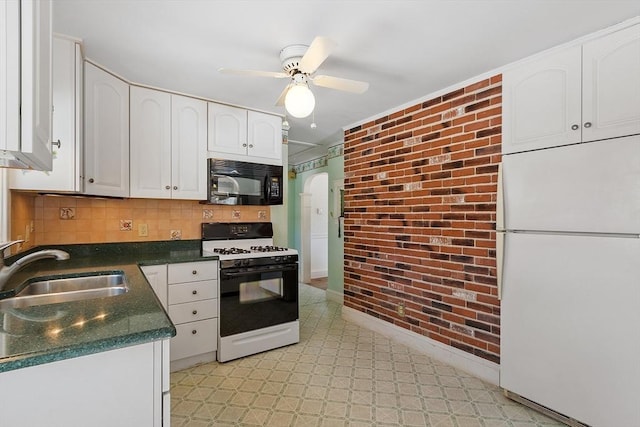 kitchen with black microwave, a sink, freestanding refrigerator, gas range oven, and dark countertops