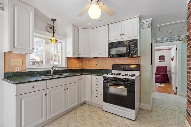 kitchen featuring black microwave, white cabinets, a sink, and gas range