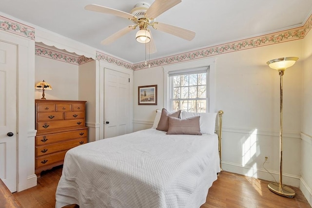 bedroom with a closet, wood finished floors, a ceiling fan, and baseboards